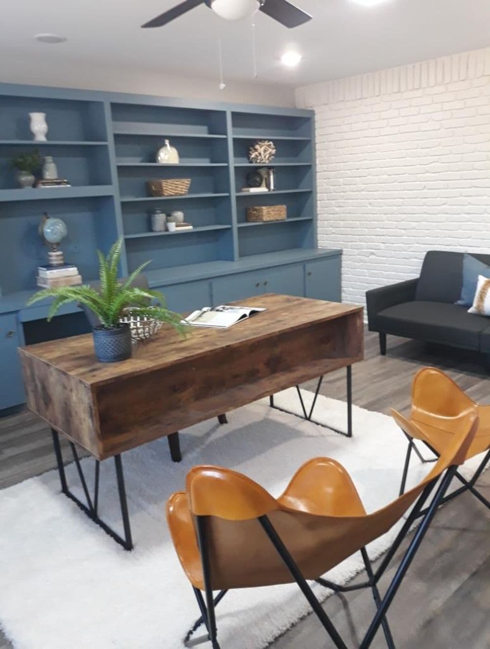 Modern home office design featuring a wooden desk, stylish chairs, and blue shelving.