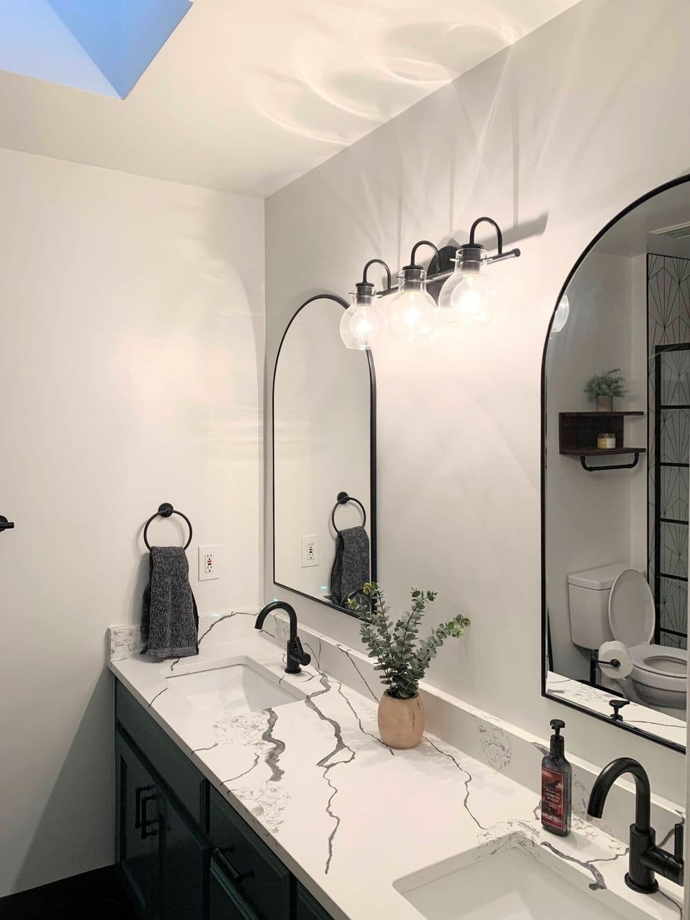 Modern bathroom interior featuring a double sink vanity with a marbled countertop and stylish lighting.