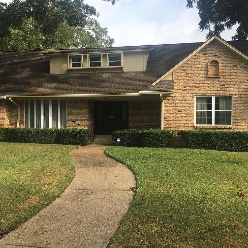 Brick house with a sloped roof, front garden, and a winding sidewalk.