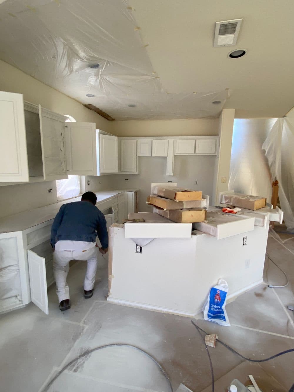 Builder working on a kitchen renovation, with cabinets and construction materials visible.