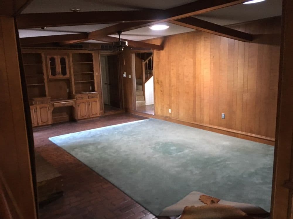Spacious wooden-paneled living room with carpet and built-in shelves.