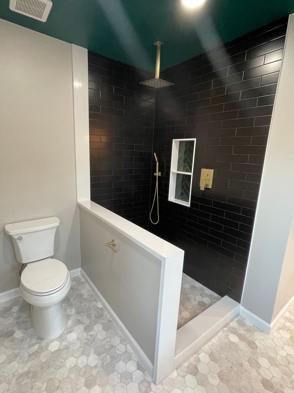 Modern bathroom featuring a walk-in shower with black tiles, a white vanity, and hexagon flooring.