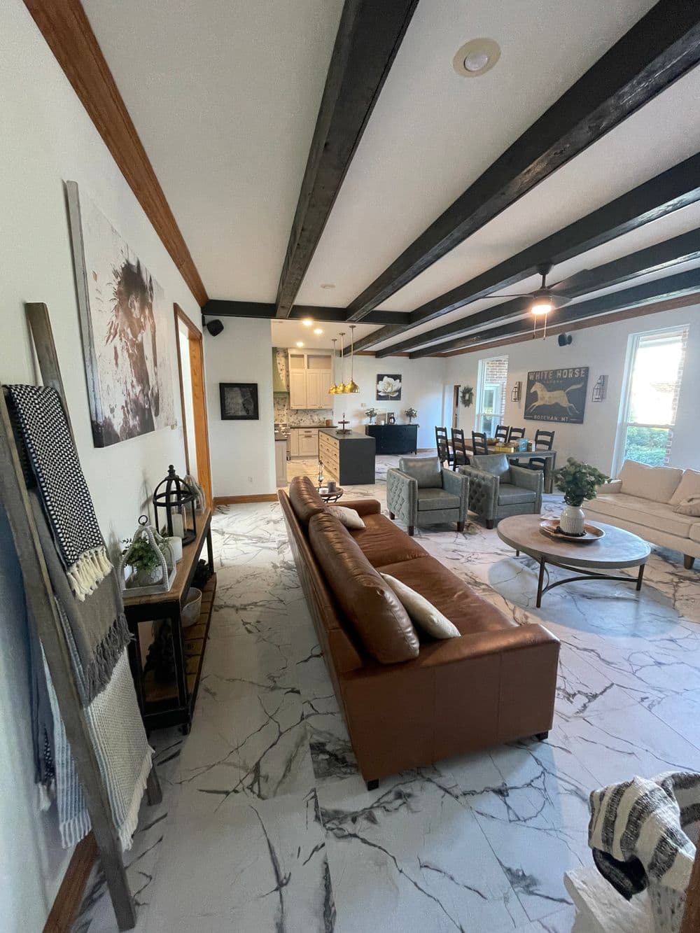 Modern living room with leather sofa, wooden beams, and stylish decor, showcasing an open layout.