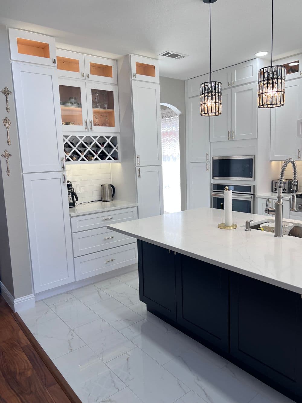 Modern kitchen featuring white and black cabinetry, marble floors, and stylish pendant lighting.