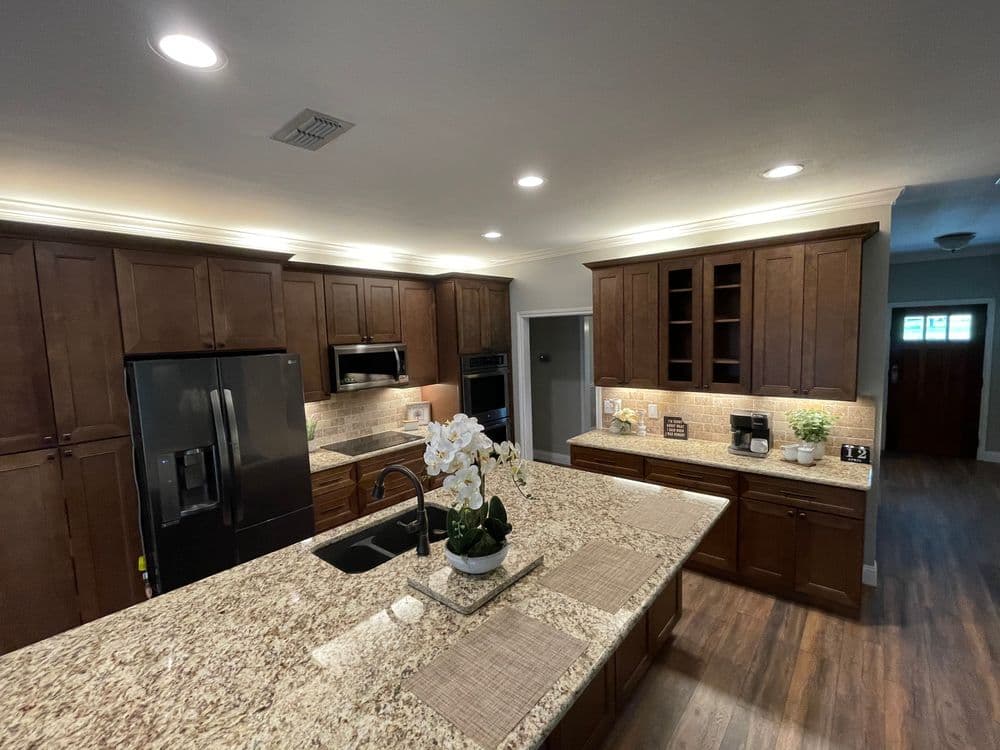 Modern kitchen with brown cabinets, granite countertops, and stainless steel appliances.