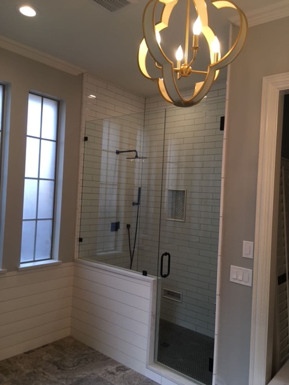 Modern bathroom featuring a glass shower, decorative chandelier, and gray walls.