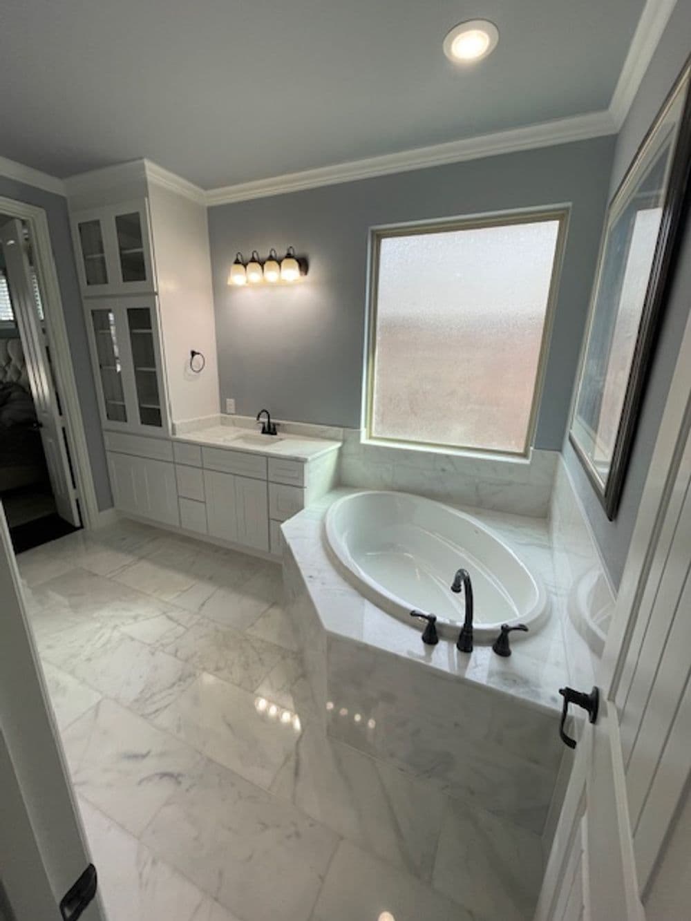 Modern bathroom featuring a large bathtub, elegant marble flooring, and natural light.