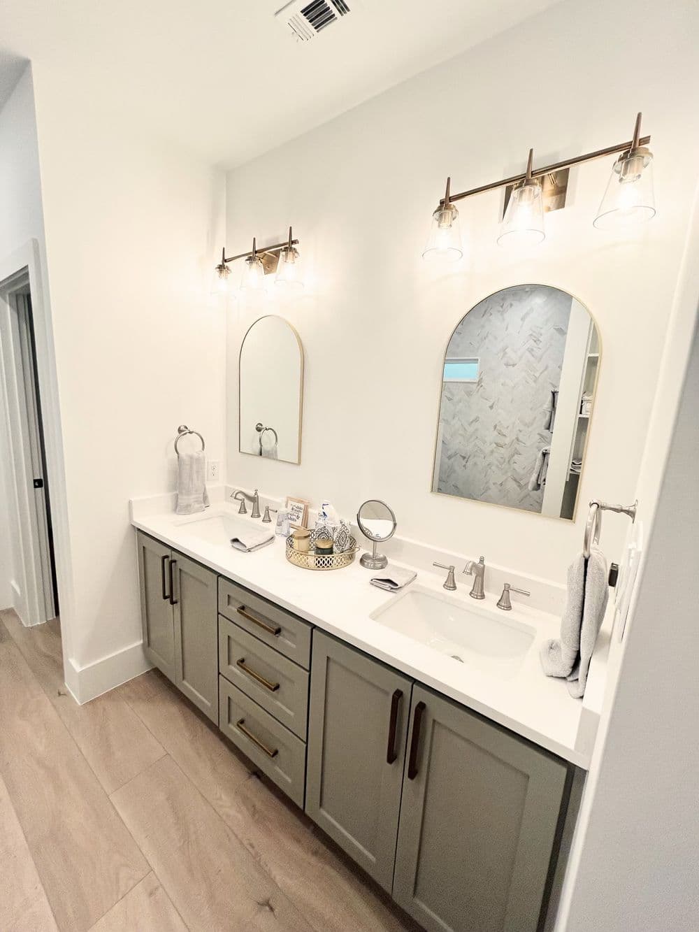 Modern bathroom with double sinks, elegant mirrors, and stylish lighting fixtures.