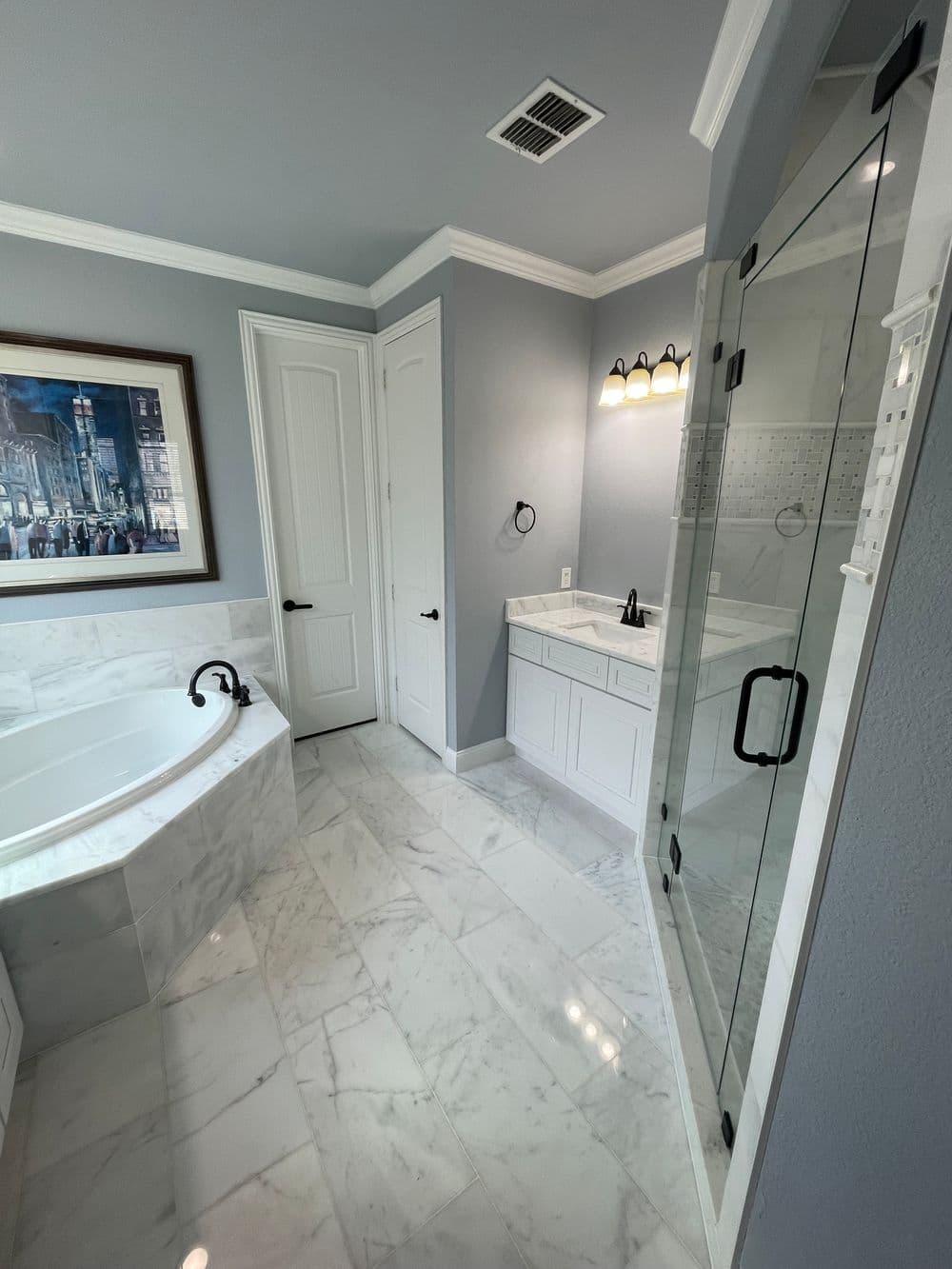 Modern bathroom featuring a marble floor, glass shower, and elegant fixtures. Bright and spacious.