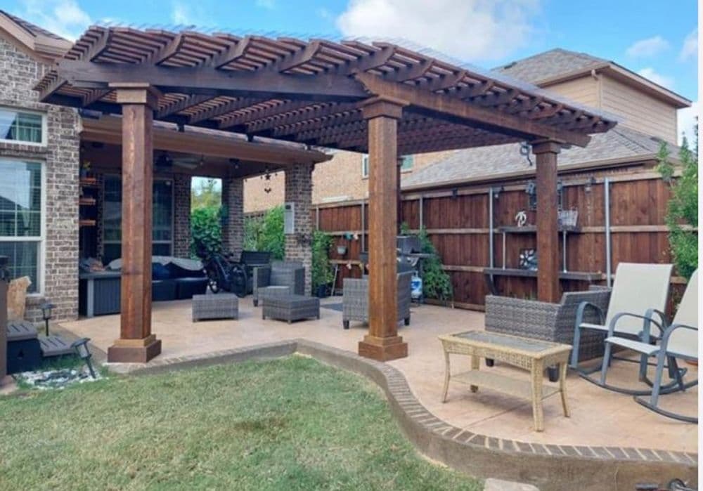 Stylish outdoor pergola with seating area and lush green lawn in a residential backyard.
