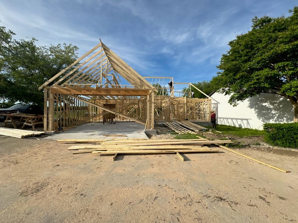New home construction featuring wooden framing under a clear blue sky.